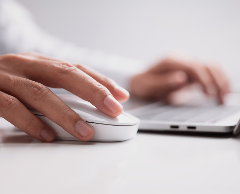 Side view of a man typing on laptop keyboard and moving mouse