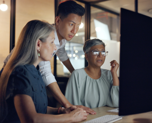 Side view of two employees being helped by an IT Professional