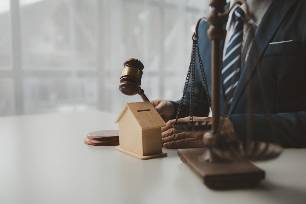 An image of a man in a suit with a gavel, scale, and symbolic representation of assets and property, all of which serve as a great visualization of what an estate administrator is and does.
